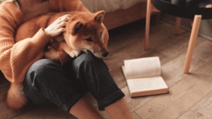woman petting her dog beside a book
