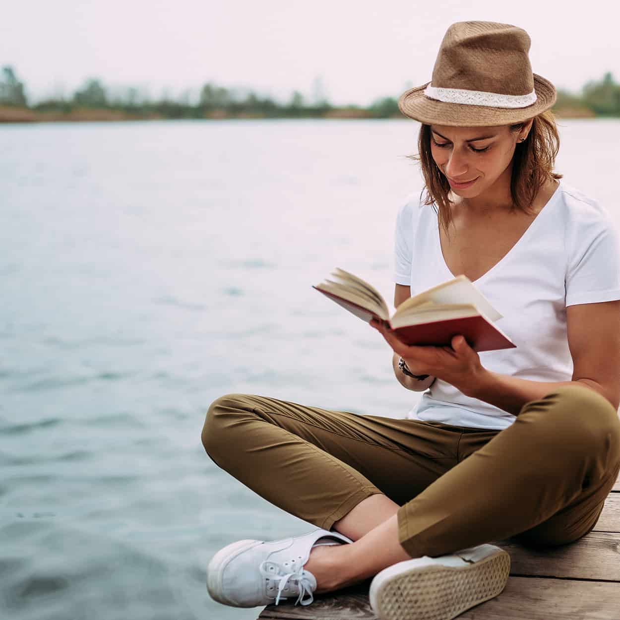 woman reading book by the water during at-home addiction rehab
