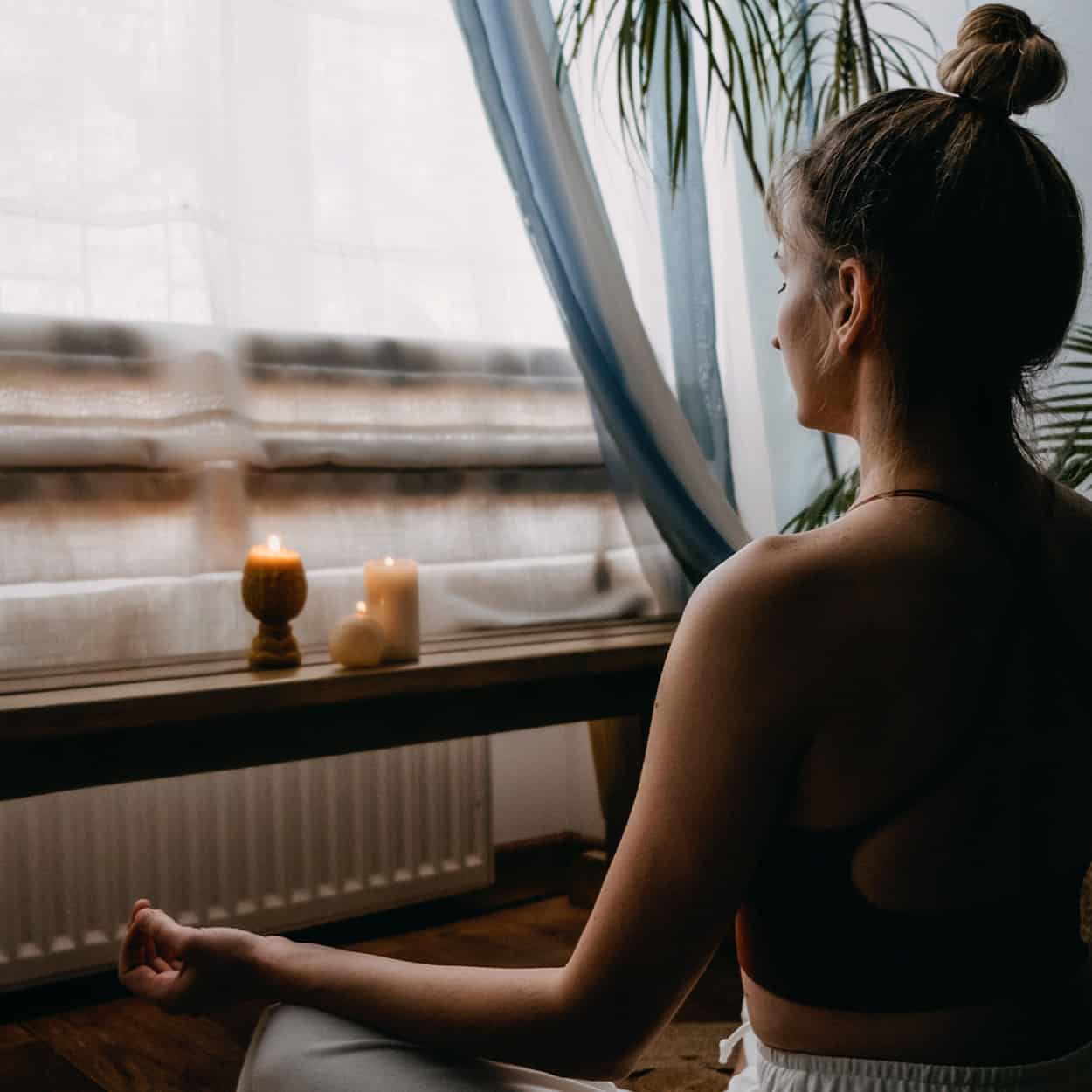 woman meditating with candles during at-home addiction rehab