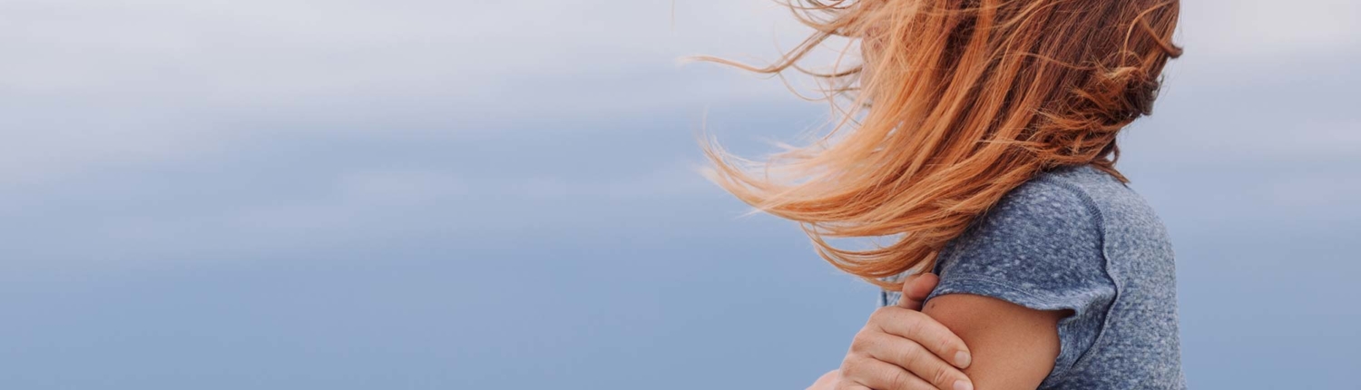 woman with crossed arms looking out over water