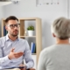 Front view of a professional man speaking to a woman in the foreground