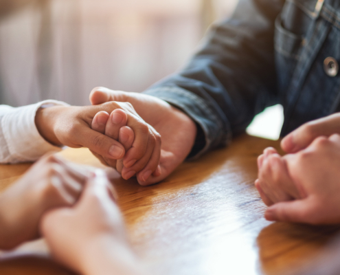 Group of people sitting in a circle holding hands
