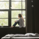 Side view of a woman sitting in a windowsill