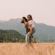 A couple walking through a field infront of mountains
