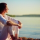 Person sitting on side of lake