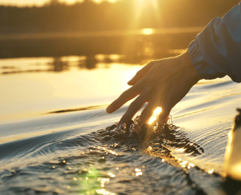 man puts fingers down in lake kayaking against backdrop of golden sunset, unity harmony nature