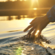 man puts fingers down in lake kayaking against backdrop of golden sunset, unity harmony nature