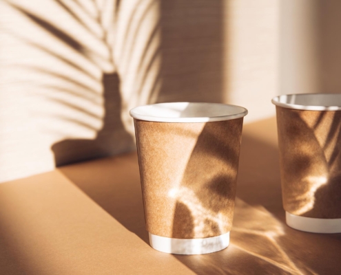Two paper cups on sunlit background with shadows