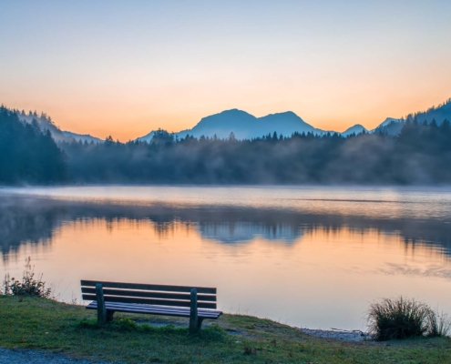 Calm park bench on lake and mountains