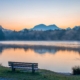 Calm park bench on lake and mountains