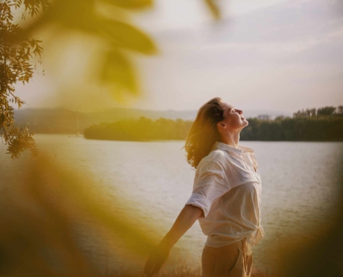 Person enjoying the breeze next to lake