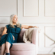 Elegant older woman wearing dress, sits on couch