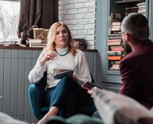Stylish professional therapist holding pen while listening to client