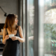 A relaxed woman in a minimalist dress leans on a rustic dining table