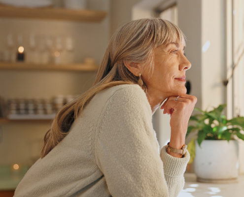 Window, smile and elderly woman with thinking at home for retirement