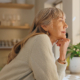 Window, smile and elderly woman with thinking at home for retirement